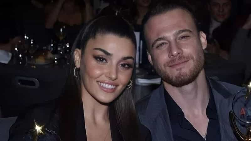 Hande Erçel smiling wearing a black dress with hair in ponytail, next to Kerem Bürsin who wears a blue costume