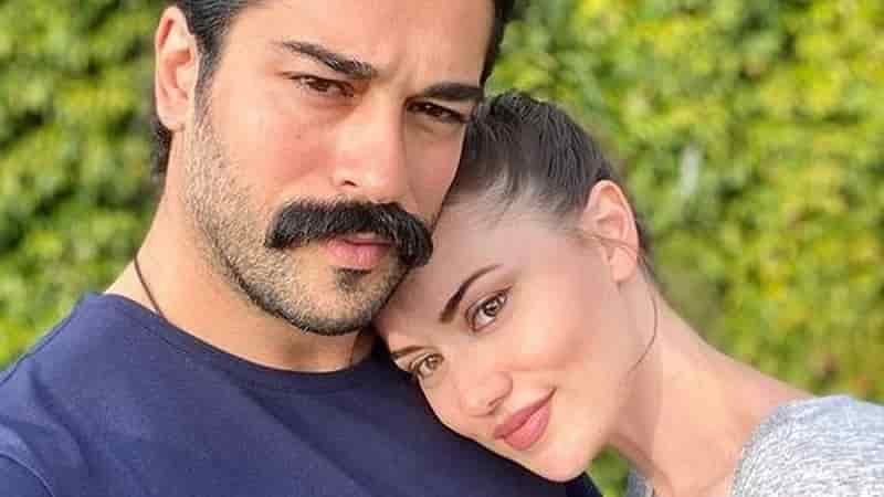 Burak Özçivit with a moustache wearing a blue navy t-shirt  with fahriye evcen holding her head on his chest waiting for second baby kerem
