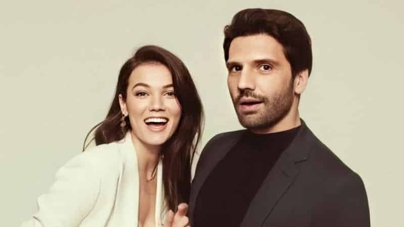 Kaan Urgancıoğlu wearing a black jacket and looking surpirsed and Pınar Deniz wearing a white jacket with long black hair with a big smile facts yargi series dizi