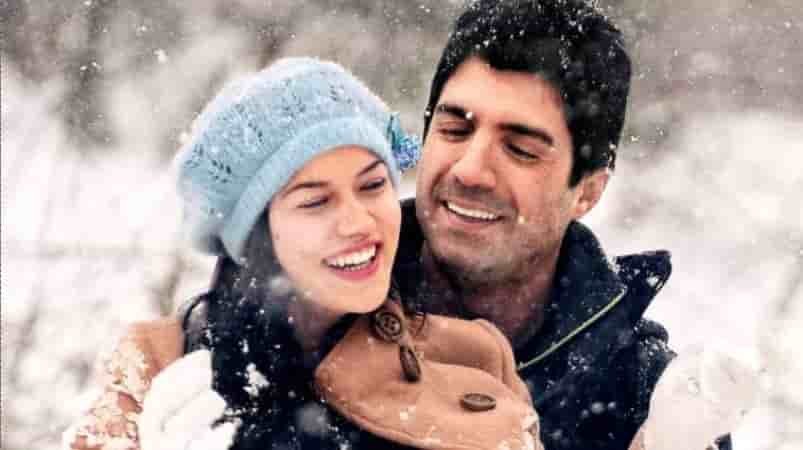 young Ozcan Deniz with black hair smiling and hugging Fahriye Evcen who wears a blue hat and white jacket, looking happy in the turkish movie evim sensin
