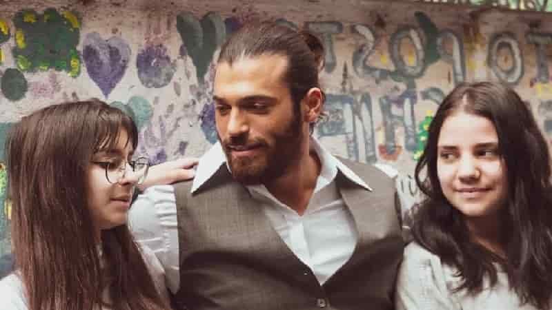 can yaman wearing a grey tuxedo and white shirt, with two children, two girls with long hair on each side