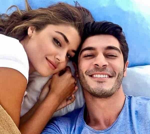 new turkish series Iki Yabanci featuring Hande Erçel wearing a white t-shirt sitting next to Burak deniz wearing a blue t-shit smiling