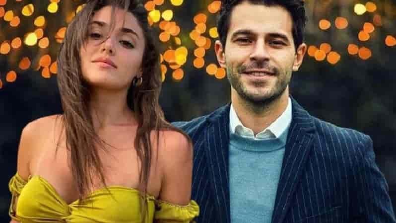 Hande Erçel wearing a yellow dress with long brown hair next to Hakan Sabancı wearing a blue blouse and a navy suit smiling