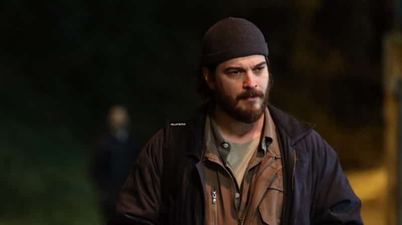 New Actor Joins Netflix Series Kübra starring Çağatay Ulusoy wearing a black cap dressed with a black jacket anad a back pack, and green shirt under