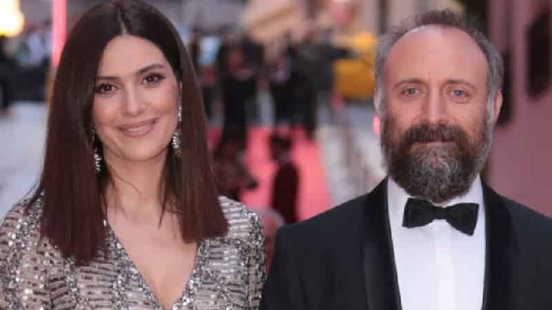 bergüzar korel wearing a sparking grey dress with a long black bob next to her husband turkish actor halit ergenç wearing a costume with a bow and white beard. married couple