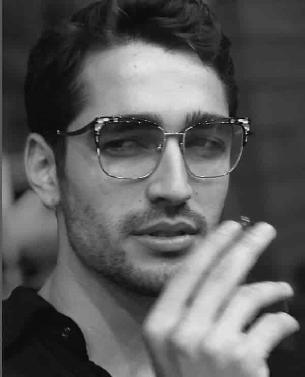 turkish actor Mert Ramazan Demir wearing glasses with beard while smoking from a cigarette aka Ferit of the dizi drama series Yalı Çapkını