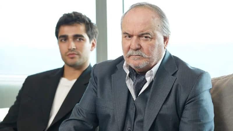 halis korhan wearing a grey suit with his nephew ferit behind his back, ferit korhan