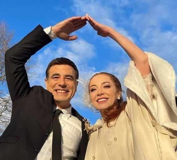 Tayanç Ayaydin and Dolunay Soysert in yabani turkish drama series as Guven and Neslihan after got married, he wears a balck suit and she wears a white jacket-dress