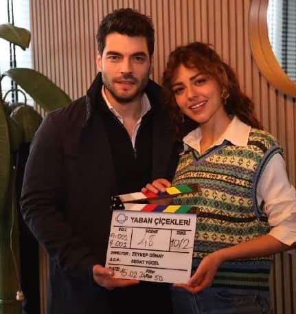 turkish actors Akın Akınözü with a black jacket next to Aslıhan Malbora with curly hair in new dizi drama series Yaban Çiçekleri