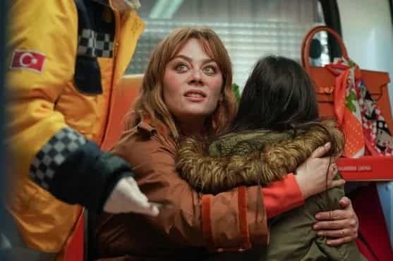 Demet Evgar wearing a brown jacket holding a child in her arms in the new turkish dizi series Bahar on show TV